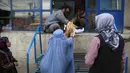 Sejumlah wanita menerima roti gratis dari kota selama lockdown untuk mencegah penyebaran virus corona, pada bulan suci Ramadan di Kabul, Afghanistan (4/5/2020). Muslim di seluruh dunia sedang menjalankan Ramadan, ketika mereka menahan diri dari makan, minum dari subuh hingga senja. (AP/Rahmat Gul)