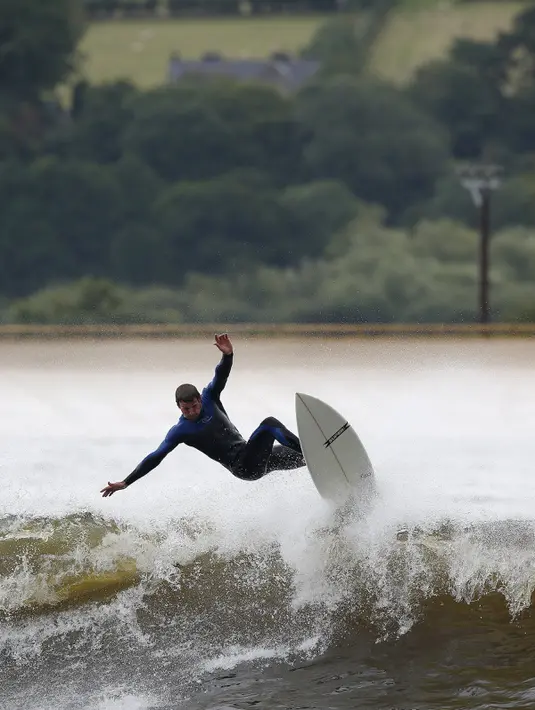 Seorang pria asik berselancar menikmati gelombang buatan yang ada di Surf Snowdonia, Conwy, North Wales, Kamis (3/9/2015).  Danau ini menjadi yang pertama sebagai Danau buatan komersial di dunia. (REUTERS/Andrew Yates)