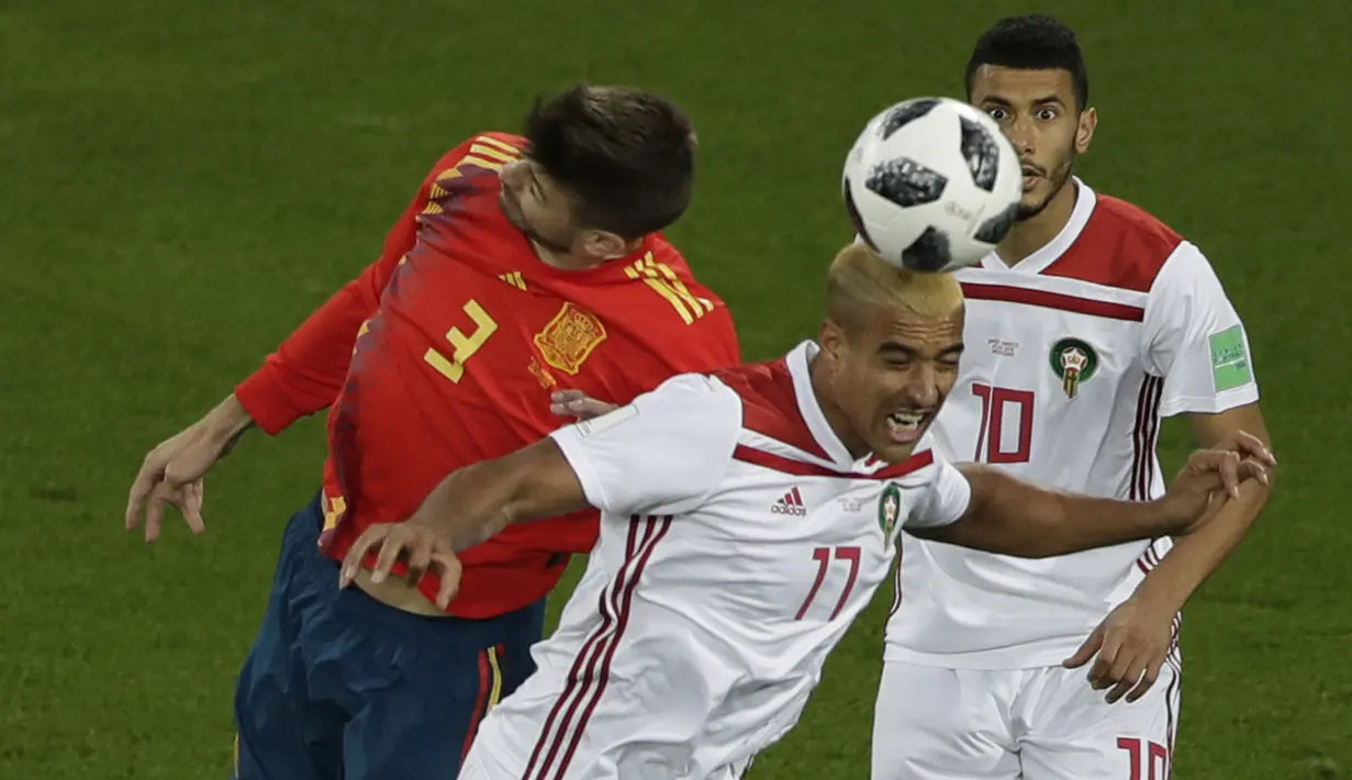 Bek Spanyol, Gerard Pique, duel udara dengan gelandang Maroko, Nabil Dirar, pada laga grup B Piala Dunia di Stadion Kaliningrad, Kaliningrad, Senin (25/6/2018). Kedua negara bermain imbang 2-2. (AP/Michael Sohn)