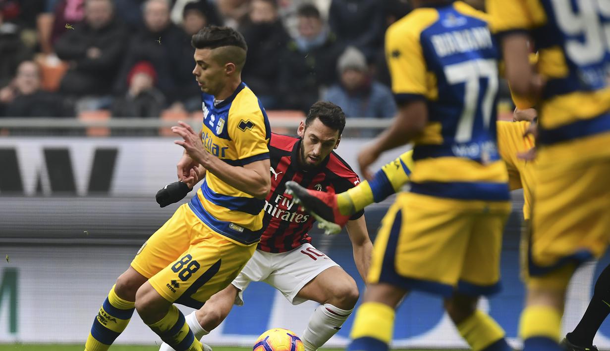 Aksi Hakan Calhanoglu saat melewati pemain Parma dalam laga lanjutan giornata ke-14 Serie A yang berlangsung di stadion San Siro, Milan, Minggu (2/12). AC Milan menang 2-1. (AFP/Miguel Medina)