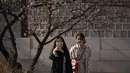 Dua wanita menggunakan ponsel berselfie di istana Changdeokgung di Seoul , Korea Selatan (2/4). Korea Selatan sedang bersiap untuk meluncurkan jaringan seluler 5G pertama di dunia pada 5 April. (AFP Photo/Ed Jones)