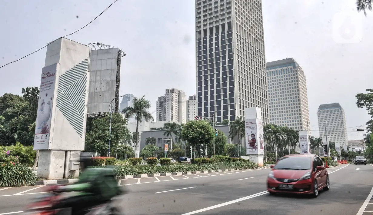 Kendaraan melintas di dekat papan reklame sosialisasi vaksin Covid-19 di tiang pancang proyek monorel, Senayan, Jakarta, Selasa (17/11/2020). Tiang pancang monorel yang terbengkalai selama 16 tahun itu dimanfaatkan oleh sebagai papan reklame sosialisasi vaksin Covid-19. (merdeka.com/Iqbal S Nugroho)