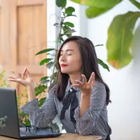 Seorang perempuan sedang melakukan pose meditasi di kantor (Foto Dok: Freepik/jcomp).