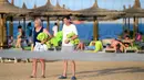 Dua orang turis berjalan di pantai kota wisata Laut Merah Mesir, Hurghada pada 3 April 2019. Sepanjang tahun Hurghada beriklim tropis, sehingga banyak turis yang datang untuk merasakan musim panas dari bulan Januari sampai Desember. (Mohamed el-Shahed / AFP)