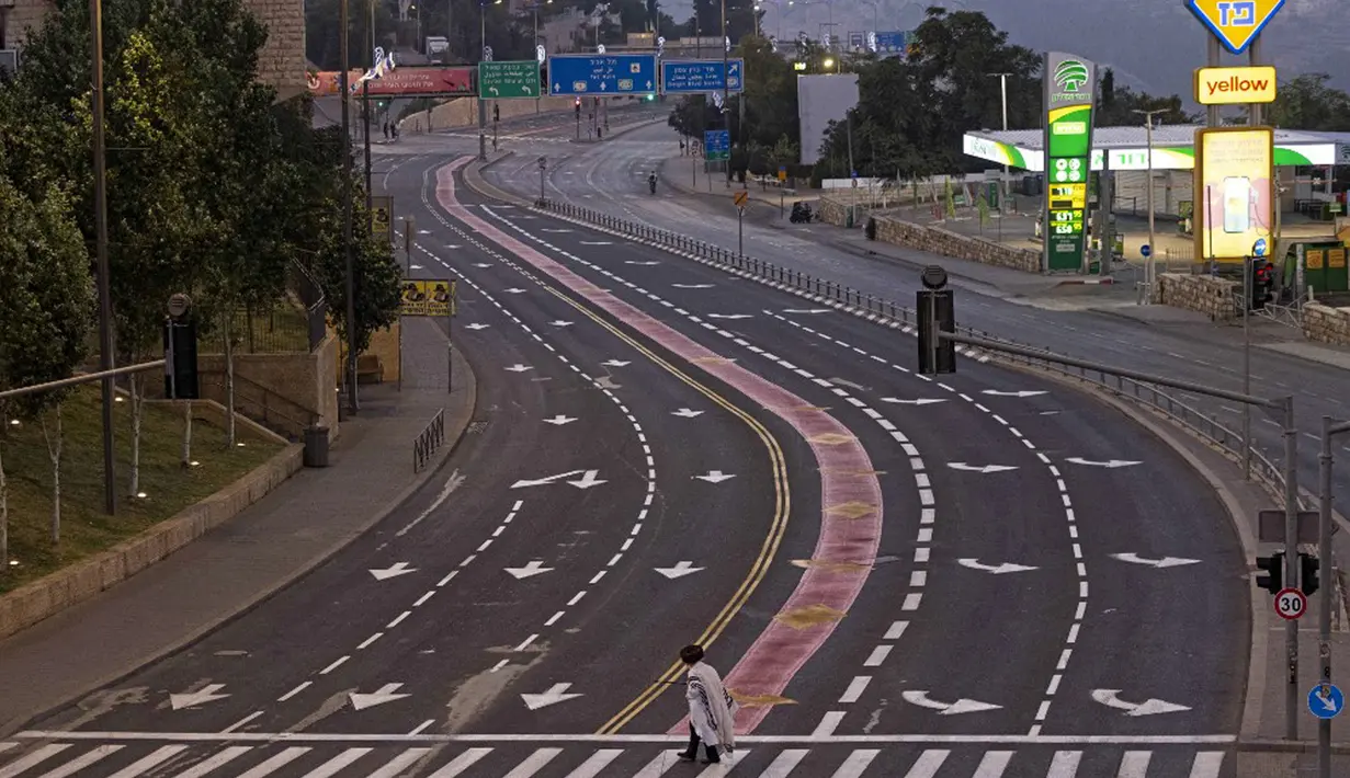 Seorang Yahudi ultraortodoks melintasi jalan raya bebas mobil saat warga Israel merayakan puasa Yom Kippur dan tidak mengemudi, Yerusalem, 4 Oktober 2022. Yom Kippur yang juga dikenal sebagai Hari Penebusan adalah salah satu hari libur terpenting Yahudi di mana orang Israel menjalankan puasa, refleksi, dan doa selama 25 jam. (MENAHEM KAHANA/AFP)