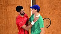 Pemenang pertandingan tenis Italia, Jannik Sinner, menyemangati Novak Djokovic (kiri) dari Serbia di akhir pertandingan semifinal tunggal putra pada hari ke-13 turnamen tenis Prancis Terbuka di Lapangan Philippe-Chatrier di Kompleks Roland-Garros di Paris pada 6 Juni 2025. (JULIEN DE ROSA/AFP)