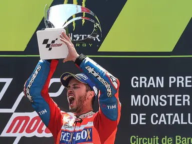 Pembalap Ducati, Andrea Dovizioso mengangkat trofi di podium setelah memenangi MotoGP Catalunya di sirkuit Barcelona Catalunya, Minggu (11/6). Dovizioso berhasil menyelesaikan balapan dengan catatan waktu tercepat 44 menit 41,518 detik. (Josep LAGO/AFP)
