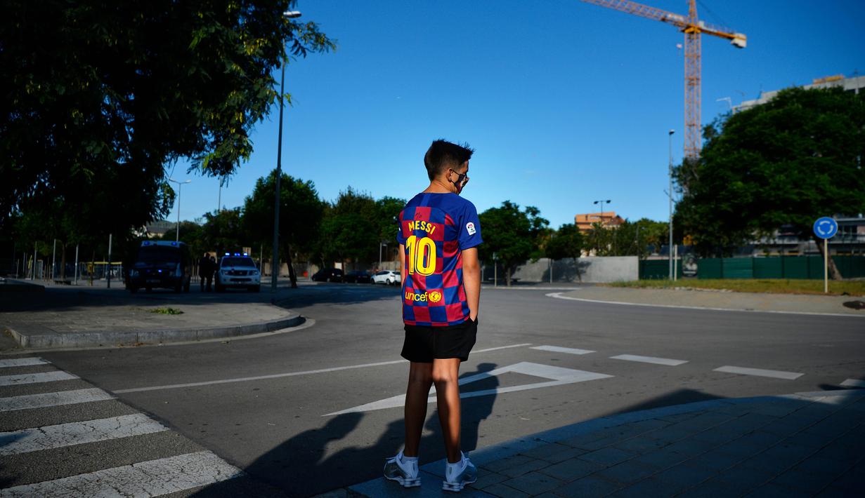 Seorang bocah saat menunggu Lionel Messi di lokasi latihan Barcelona, Senin (31/8/2020). Messi secara mengejutkan tidak datang untuk mengikuti tes swab Covid-19 yang dijadwalkan Barcelona. (AFP/Pau Barrena)