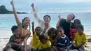 Gisella dan Naysila tampak berbaur dengan anak-anak lokal di pantai berpasir putih. Mereka duduk bersama sambil bermain dan tertawa, menunjukkan kehangatan dan kebersamaan yang tulus di tengah keindahan alam. (Liputan6.com/IG/@gisel_la)