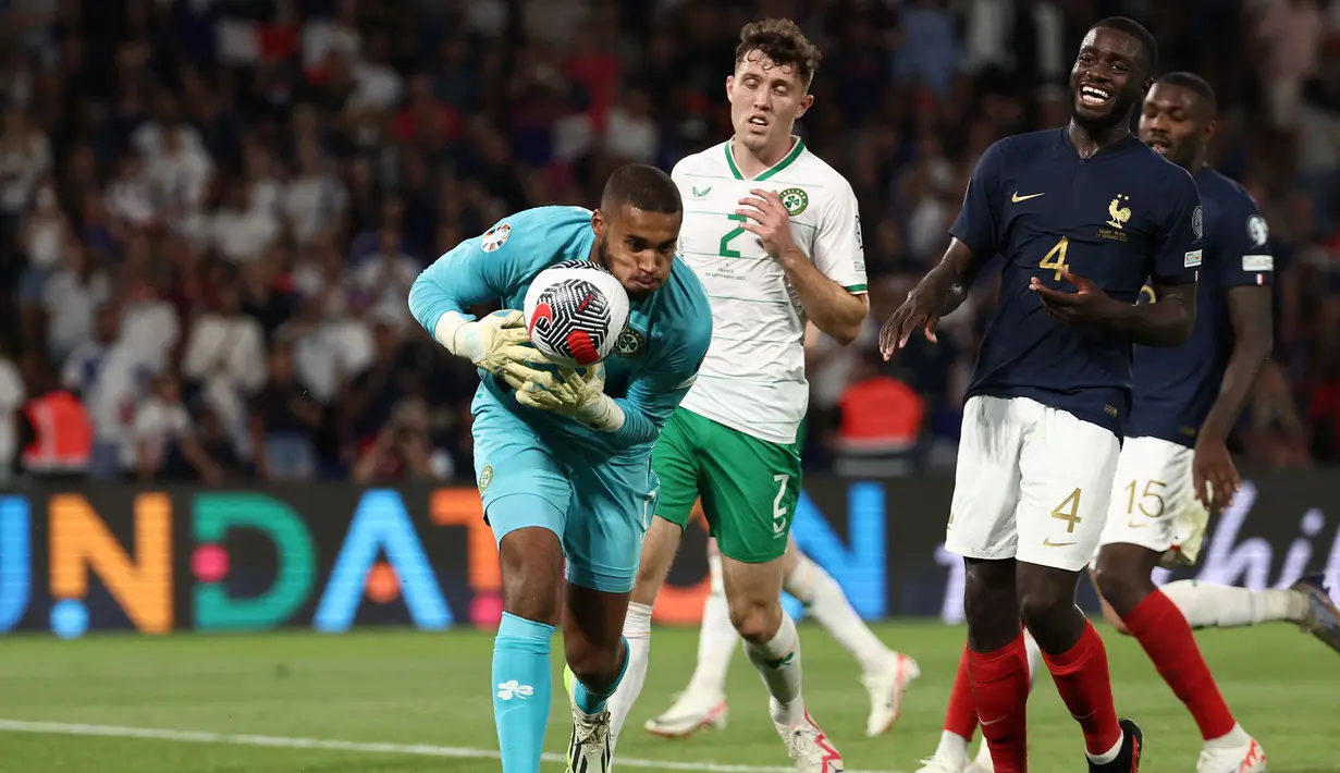 Kiper Timnas Republik Irlandia, Gavin Bazunu berhasil mengamankan bola dari ancaman bek Timnas Prancis, Dayot Upamecano pada laga Grup B Kualifikasi Euro 2024 di Parc des Princes Stadium, Paris, Jumat (8/9/2023) dini hari WIB. (AFP/Franck Fife)