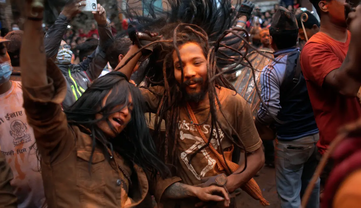 Warga menyanyi dan menari saat mengikuti perayaan sindoor Jatra festival di Bhaktapur, Nepal (15/4). Festival tahunan ini diwarnai dengan bubuk vermillion berwarna oranye yang terbalur pada sekujur tubuh para peserta. (AP Photo/Niranjan Shrestha)
