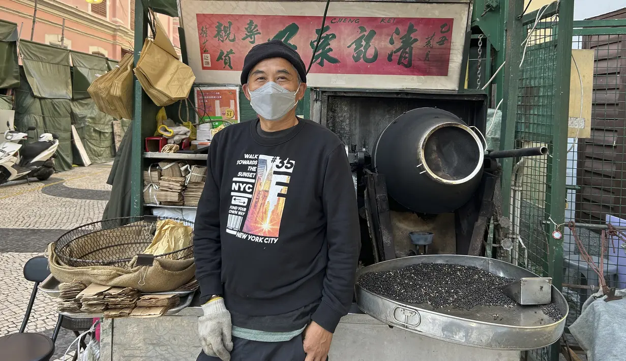 Antony Chau, yang menjual chestnut panggang, berdiri di tokonya pada 28 Desember 2022, di Senado Square, di Macao.  “Wisatawan hanya datang ke sini untuk jalan-jalan daripada berbelanja,” kata Chau. "Mereka hanya berkeliaran." (AP Photo/Kanis Leung)