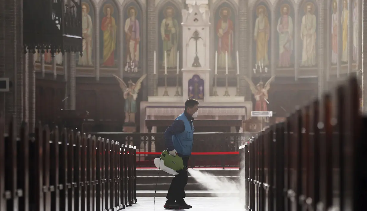 Pekerja memakai masker menyemprotkan disinfektan sebagai tindakan pencegahan virus corona COVID-19 di Katedral Myeongdong di Seoul, Korea Selatan, Rabu, (26/2/2020). Jumlah infeksi corona di Korea Selatan melonjak lagi pada Rabu (26/2). (Lee Ji-eun/Yonhap via AP)