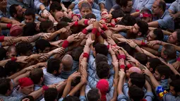 Para Castellers membentuk fondasi untuk menara manusia atau ‘Castell’ di alun-alun Sant Jaume, Barcelona, Spanyol, Minggu (24/9). Ribuan orang separatis Catalonia mendukung referendum kemerdekaan bagian timur Spanyol tersebut. (AP Photo/Emilio Morenatti)