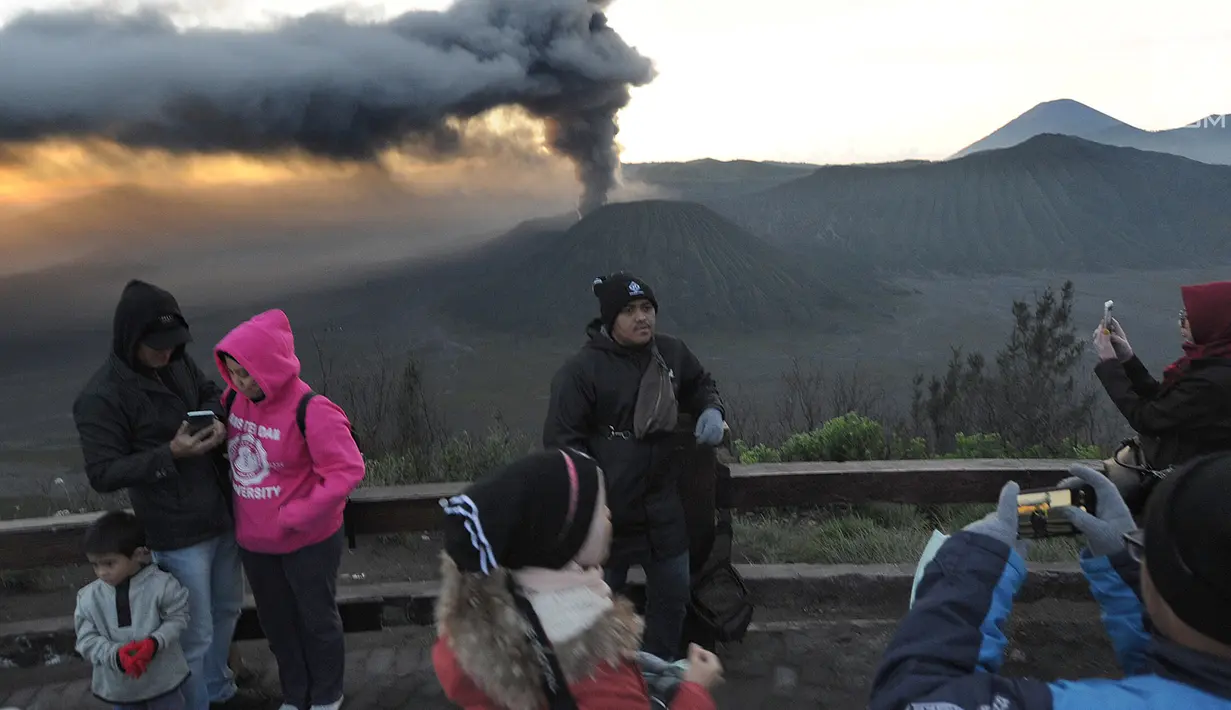 Wisatawan berpose dengan latar belakang gunung Bromo yang sedang mengalami erupsi di Probolinggo, Jawa Timur, Selasa (26/3/2019). Aktivitas vulkanis Gunung Bromo masih berada di level II waspada, meski sedang mengalami erupsi pada beberapa hari belakangan ini. (merdeka.com/Arie Basuki)