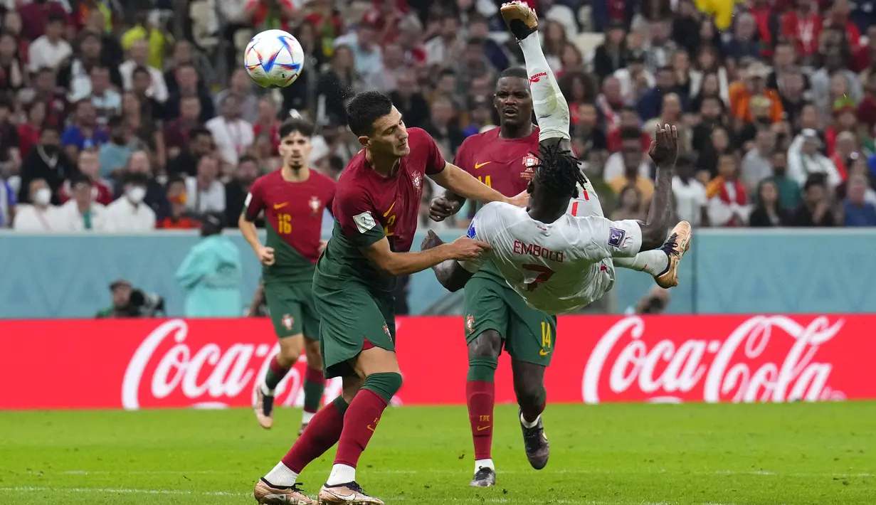 Penyerang Swiss Breel Embolo berebut bola dengan bek Portugal Diogo Dalot dalam laga 16 besar Piala Dunia 2022 di Stadion Lusail Iconic, Rabu (7/12/2022) dini hari WIB. Portugal menjadi tim terakhir yang menyegel tiket ke perempatfinal Piala Dunia 2022. (AP Photo/Natacha Pisarenko)