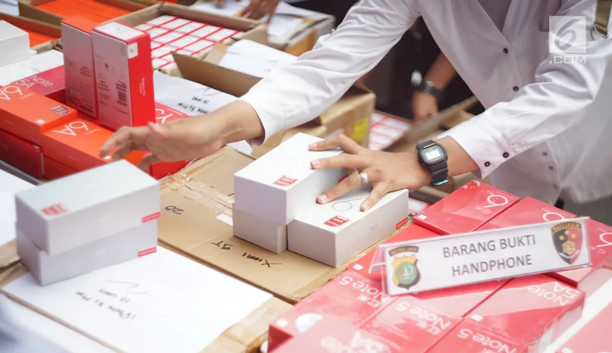 Petugas kepolisian merapikan barang bukti kasus penyelundupan perangkat telekomunikasi elektronik di Polda Metro Jaya, Jakarta, Kamis (29/8/2019). Polda Metro Jaya menangkap empat orang pelaku penyelundupan 5.572 handphone (HP) berbagai merek dari China ke Jakarta. (Liputan6.com/Immanuel Antonius)