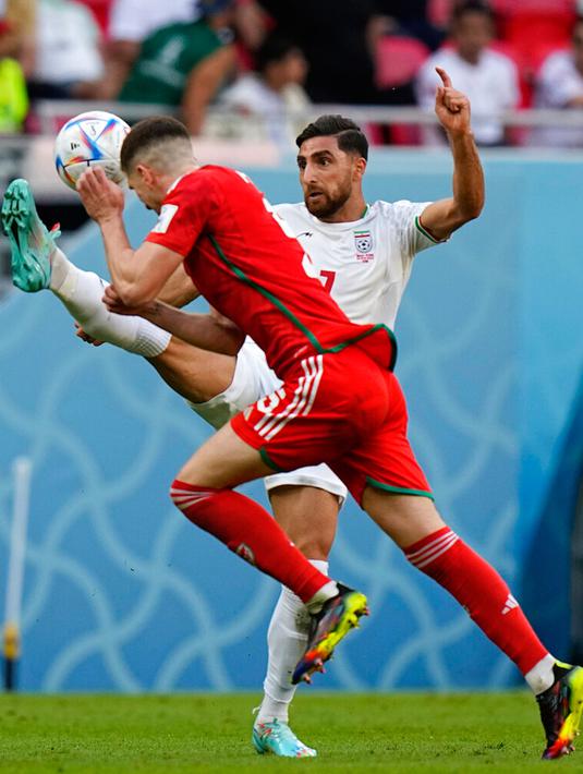 Pemain Iran Alireza Jahanbakhsh (kanan) menendang bola saat pemain Wales Chris Mepham bertahan pada pertandingan sepak bola Grup B Piala Dunia 2022 di Stadion Ahmad Bin Ali, Al Rayyan, Qatar, Jumat (25/11/2022). Iran mengalahkan Wales dengan skor 2-0. (AP Photo/Pavel Golovkin)