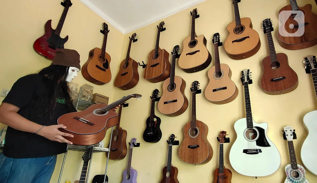 Pemilik showroom dan bengkel Gitar "music666", Ridwan dan Rudi mendemonstrasikan gitar yang akan dijual secara daring di Ciledug, Tangerang, Rabu (22/7/2020). Pemerintah menargetkan 10 juta usaha mikro kecil menengah (UMKM) pada tahun ini terhubung dengan platform digital (Liputan6.com/Angga Yuniar)