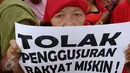 Seorang ibu memperlihatkan poster berisi tuntutan saat menggelar unjuk rasa di depan Balai Kota DKI Jakarta, Kamis (3/11). Dalam aksinya, mereka menolak penggusuran terhadap rakyat miskin dan menuntut penurunan harga sembako. (Liputan6.com/Faizal Fanani)