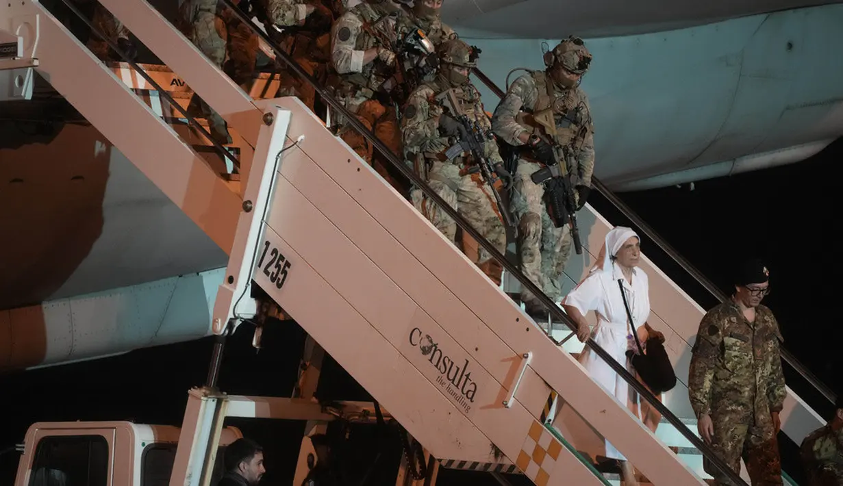 <p>Seorang biarawati diikuti tentara Angkatan Darat Italia turun dari pesawat Angkatan Udara yang membawa warga Italia dari Sudan di Bandara Militer Ciampino, Roma, Italia, Senin (24/4/2023). (AP Photo/Gregorio Borgia)</p>