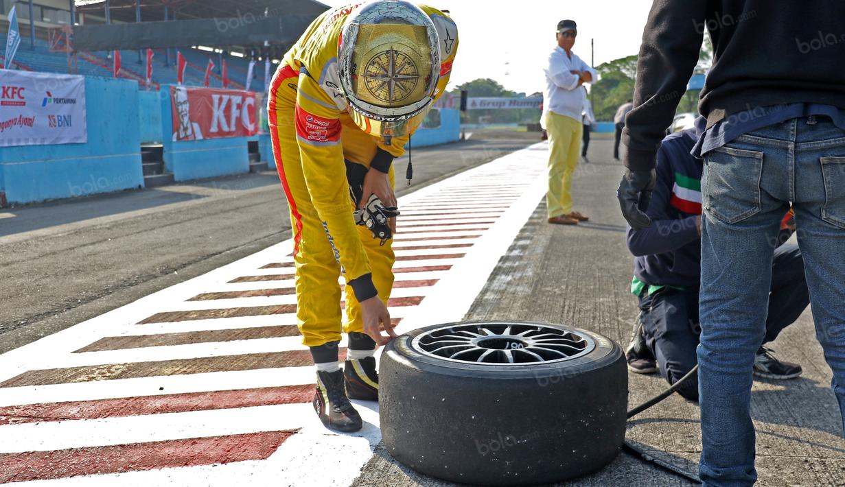 Sean Gelael melakukan pengecekan ban mobil Lamborghini sebelum dipakai pada ajang Taxi Ride d Sentul, Jakarta, Selasa (2/8/2016). (Bola.com/Nicklas Hanoatubun)