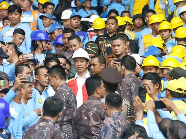 Para pekerja konstruksi berebut foto dengan Presiden Joko Widodo (Jokowi) di Stadion GBK, Jakarta, Kamis (19/10). Jokowi akan menyaksikan sertifikasi 9.700 tenaga kerja konstruksi di seluruh Indonesia secara serentak. (Liputan6.com/Angga Yuniar)