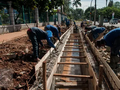 Sejumlah pekerja menyelesaikan pembuatan saluran air di Jalan Asia Afrika, Senayan, Jakarta, Rabu (5/4). Pembuatan saluran air tersebut untuk menanggulangi genangan air saat hujan turun. (Liputan6.com/Gempur M Surya)