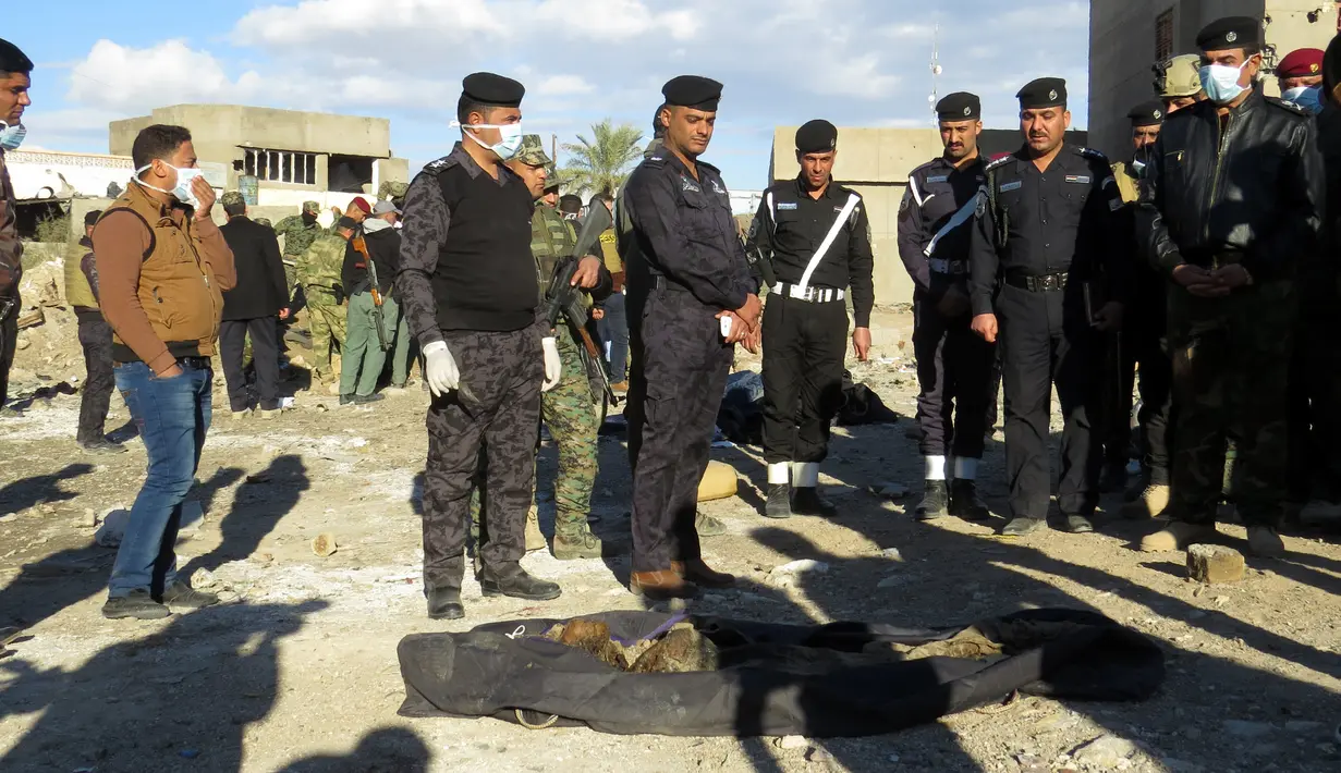 Polisi Irak berdiri di dekat jasad yang dieksekusi oleh kelompok ISIS di sebuah kuburan massal di Kota Ramadi, sebelah barat Baghdad, Selasa (26/1). Kuburan massal tersebut berisi sisa-sisa sekitar 40 jasad. (AFP/ MOADH AL-DULAIMI)