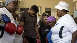 Para nenek berdoa sebelum latihan tinju pada Boxing Gogos di Cosmo City, Johannesburg, Selasa (19/9/2017). Berkat latihan rutin yang dipimpin Claude Maphosa ini para lansia berhasil sembuh dari penyakit dan hidup lebih sehat. (AFP/Gulshan Khan) 