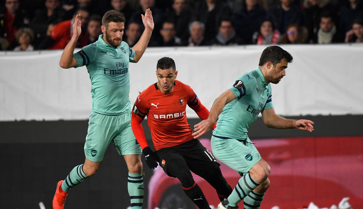 Gelandang Rennes, Hatem Ben Arfa lewati Sokratis pada leg 1, babak 16 besar Liga Europa yang berlangsung di Stadion Roazhon Park, Rennes, Jumat (8/3). Arsenal kalah 1-3 kontra Rennes. (AFP/Damien Meyer)
