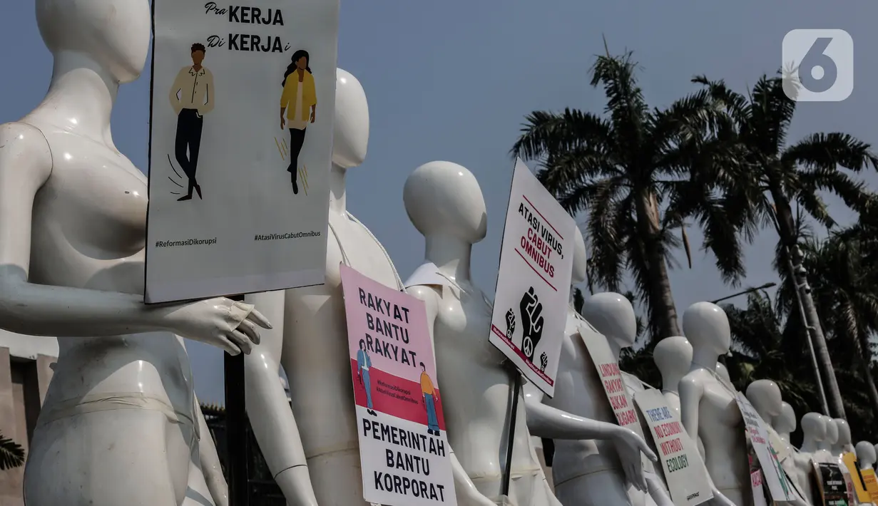 Aktivis Greenpeace Indonesia memasang poster pada puluhan maneken saat menggelar aksi damai di depan gerbang kompleks DPR, Jakarta Pusat, Senin (29/6/2020). Aksi tersebut dilakukan sebagai bentuk penolakan terhadap RUU Omnibus Law. (Liputan6.com/Johan Tallo)