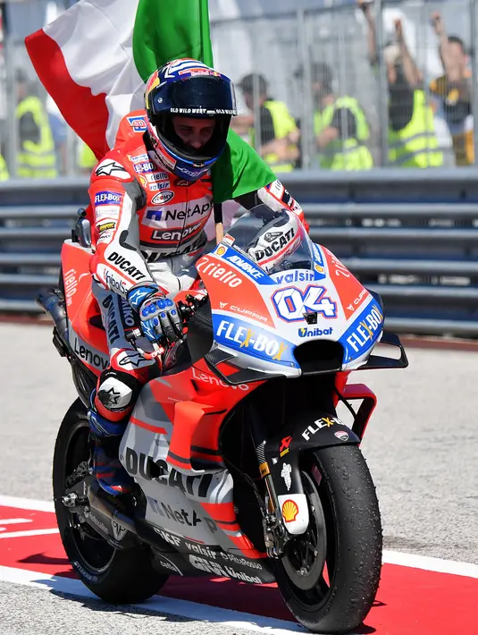 Pembalap Ducati, Andrea Dovizioso tiba di pit membawa bendera Itali usai memenangkan balapan MotoGP San Marino di Sirkuit Marco Simoncelli, Misano (9/9). Dovizioso mencetak waktu 42 menit 5,426 detik. (AFP FOTO / Tiziana Fabi)