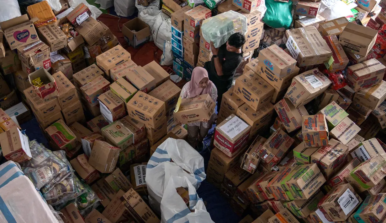 Para relawan mengemasi perlengkapan untuk dikirimkan ke daerah-daerah terdampak banjir di Badan Penanggulangan Bencana Daerah (BPBD) Sidoarjo, Provinsi Jawa Timur, pada Jumat 5 Desember 2025. (JUNI KRISWANTO/AFP)