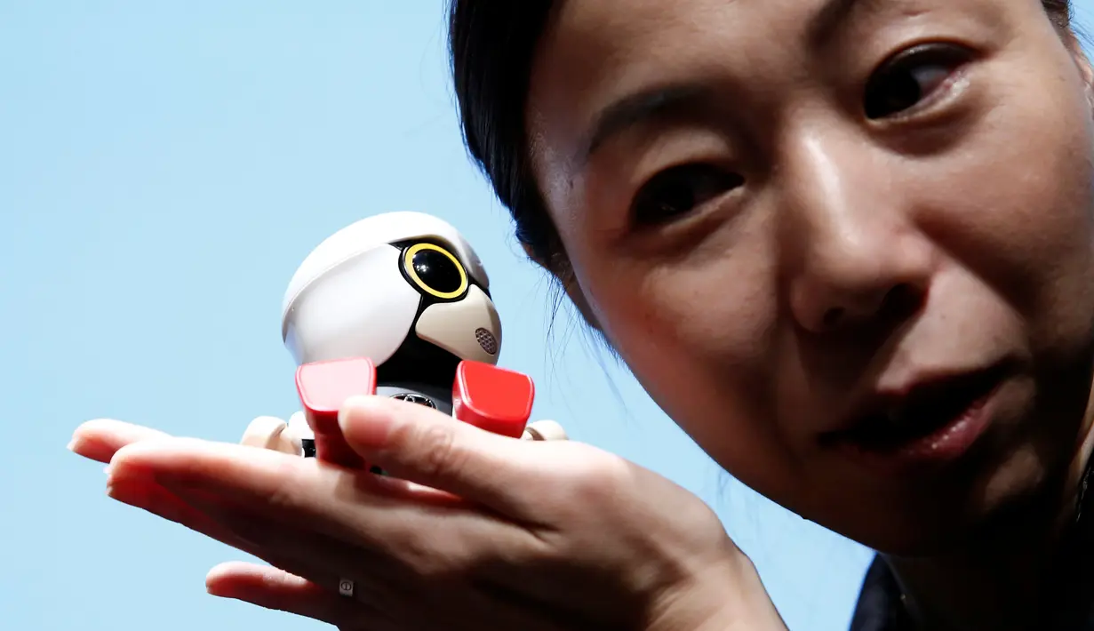 Seorang wanita memegang Robot Mini Kirobo saat diperkenalkan di Tokyo, Jepang pada 27 September 2016. Toyota masih menggembangkan keterampilan Kirobo Mini agar memiliki lebih banyak kemampuan. (REUTERS/Kim Kyung-Hoon)
