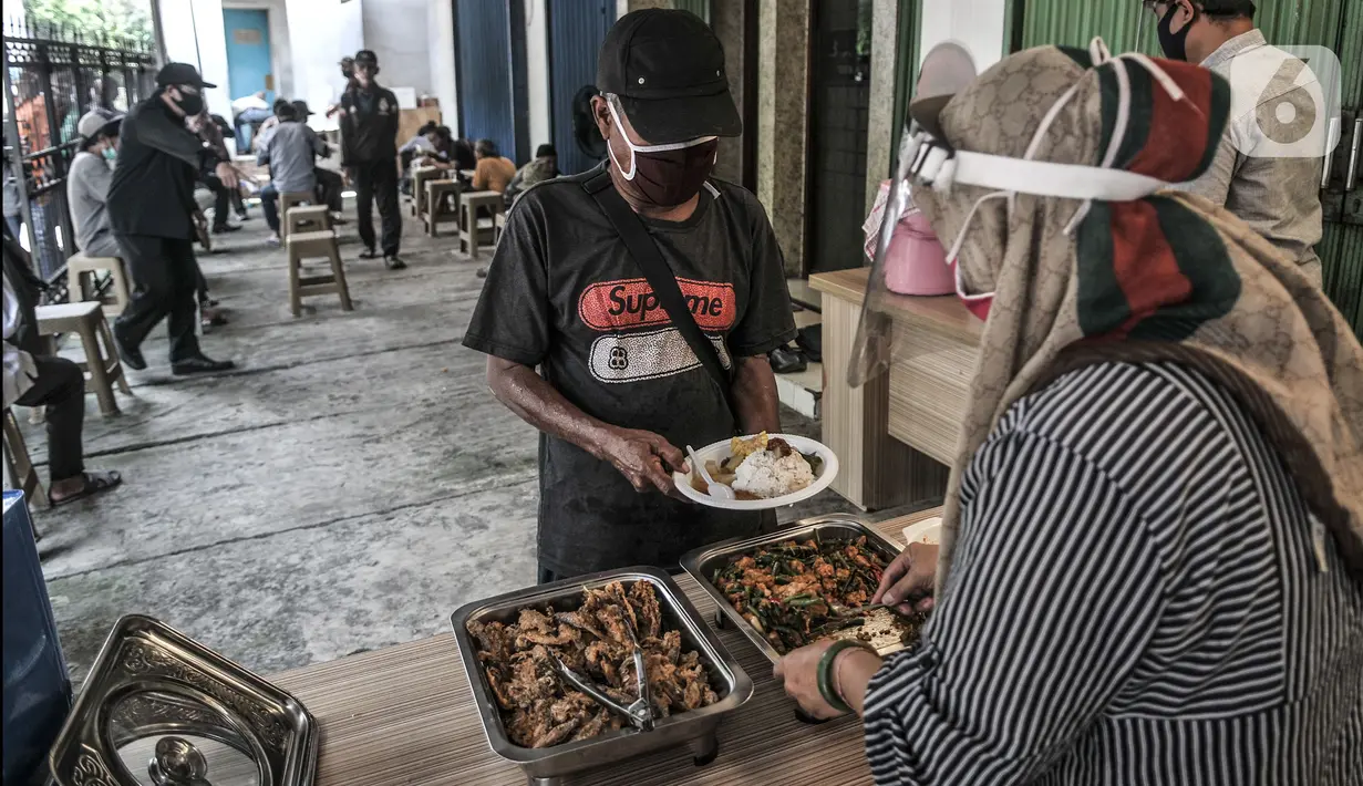 Warga mengambil makanan gratis di Jalan Basuki Rachmat, Cipinang Muara, Jakarta, Senin (8/3/2021). Sejak Juli 2020, Hadi (40) dibantu teman-temannya menggelar layanan makan gratis kepada warga