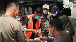 Warga yang terjaring razia masker didata petugas Satpol PP di kawasan Tanjung Duren, Jakarta, Kamis (19/11/2020). Satpol PP terus menindak warga yang melanggar protokol kesehatan selama PSBB transisi dengan sanksi kerja sosial di sarana umum atau membayar denda. (merdeka.com/Imam Buhori)