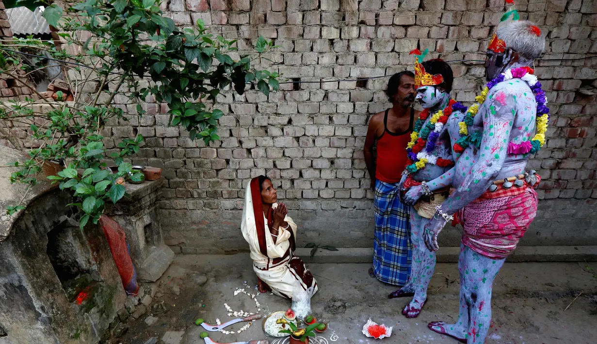 Seorang wanita (kiri) berdoa dihadapan sejumlah umat hindu yang mengecat tubuhnya selama ritual dalam festival keagamaan Siwa Gajan di Bengal Barat , India , (11/4).Kegiatan ini juga menandai akhir tahun kalender Bengali. (REUTERS / Rupak De Chowdhuri)