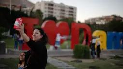 Seorang wanita Suriah dan anaknya berselfie dengan karya seni di balik pernyataan "I Love Damascus" di Omayyid Square, di Damaskus, Suriah, (18/7). (AP Photo / Hassan Ammar)