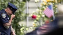 Petugas New York City Police Department (NYPD) menangis saat menghadiri upacara peringatan 16 tahun korban serangan 11 September di Museum dan Memorial Nasional 9/11, New York, Amerika Serikat, Senin (11/9). (Drew Angerer/Getty Images/AFP)