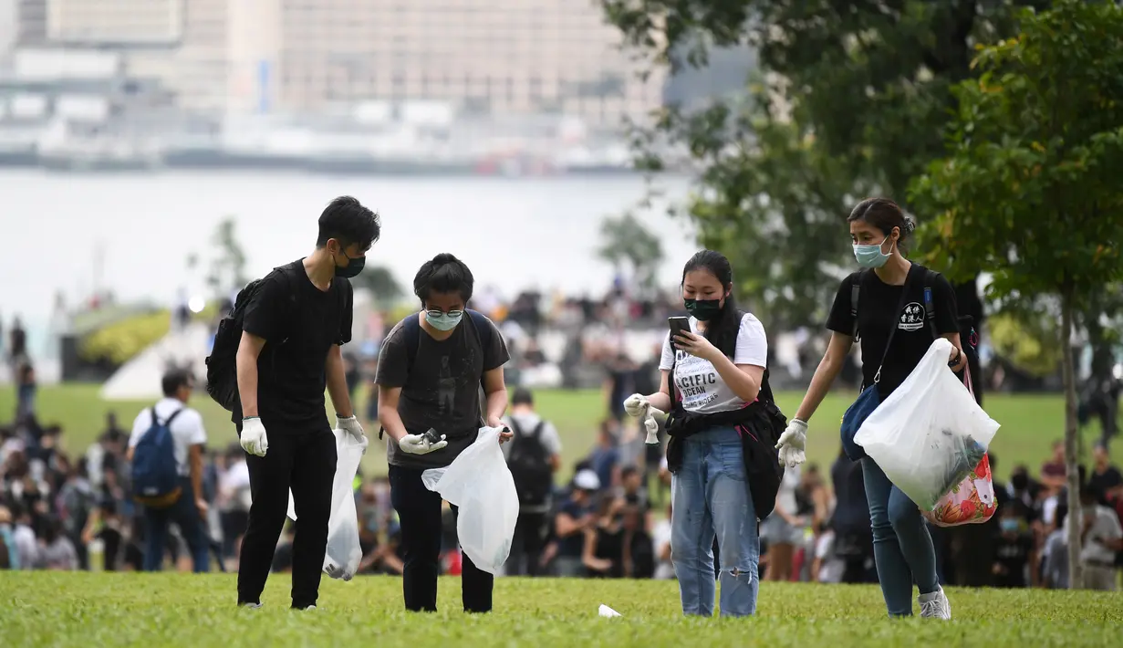 Relawan membersihkan sampah di sebuah taman dekat markas pemerintah setelah demonstrasi menolak RUU ekstradisi di Hong Kong (13/6/2019). Aksi tersebut berujung bentrok antara polisi dan warga dimana puluhan ribu orang memblokir jalan-jalan di kota tersebut. (AFP Photo/Anthony Wallace)