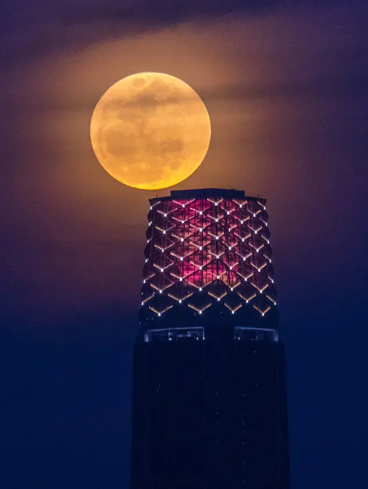 Bulan purnama muncul di belakang The Exchange 106 juga dikenal sebagai TRX Tower di Kuala Lumpur, Malaysia, 14 Juni 2022. Fenomena ini disebut juga sebagai Strawberry Supermoon karena terjadi pada saat panen strawberry. (AP Photo/Vivian Lo)
