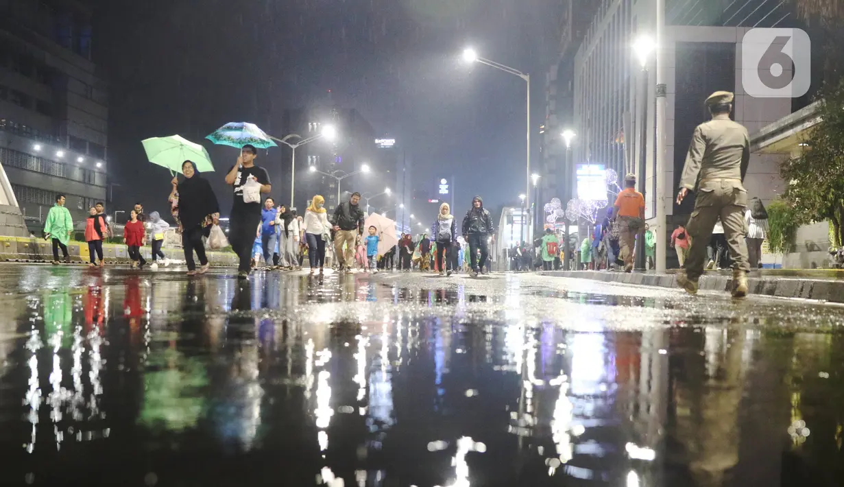 Masyarakat mulai memadati car free night di kawasan Thamrin, Jakarta, Selasa (31/12/2019). Meski diguyur hujan masyarakat mulai memadati kawasan tersebut untuk menikmati malam pergantian tahun 2019. (Liputan6.com/Angga Yuniar)