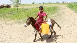 Seorang anak perempuan pengungsi internal Yaman tiba dengan menunggang keledai di tempat penampungan air untuk mengisi jeriken di Distrik Abs, Provinsi Hajjah, Yaman, 10 Oktober 2026. (Essa Ahmed/AFP)