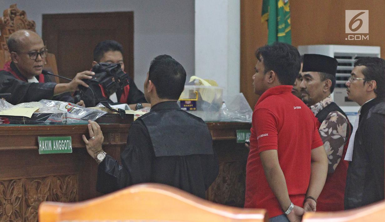 Gatot Brajamusti melihat barang bukti untuk kepemilikan senjata api diruang sidang di PN Jakarta Selatan, Selasa (7/11). Barang bukti itu dikeluarkan jaksa dari tas hitam dan ditunjukkan satu per satu di meja majelis hakim. (Liputan6.com/Herman Zakharia)