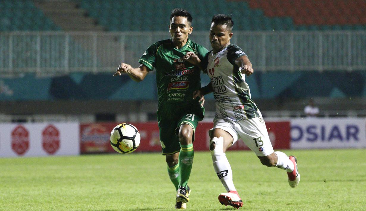 Gelandang PSMS Medan, Frets Butuan, berebut bola dengan gelandang PS Tira, Manahati Lestusen, pada laga Liga 1 di Stadion Pakansari, Jawa Barat, Rabu (5/12). PSMS kalah 2-4 dari PS Tira. (Bola.com/Yoppy Renato)