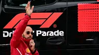 Pembalap Ferrari,  Lewis Hamilton, melambaikan tangan ke fans saat parade pembalap sebelum balapan F1 GP Inggris di Sirkuit Silverstone, Minggu (6/7/2025). (AFP/Ben Stansal)