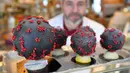 Pembuat cokelat, Jean-François Pre menunjukkan telur paskah berbentuk seperti Virus Corona di tokonya di Landivisiau, Prancis, 7 Maret 2020. Cokelat ini terbuat dari cokelat putih yang diberikan pewarna hitam serta dipadukan dengan kacang almond yang diwarnai merah. (Damien MEYER/AFP)