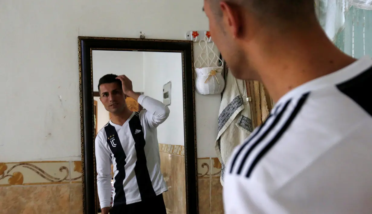 Pemain sepak bola Kurdi Irak, Biwar Abdullah (25) melihat ke sebuah cermin di rumahnya distrik Soran, timur laut Erbil, 6 April 2019. Biwar Abdullah menjadi selebritis dadakan dan terkenal karena kemiripan wajahnya dengan bintang Juventus, Cristiano Ronaldo. (REUTERS/Azad Lashkari)