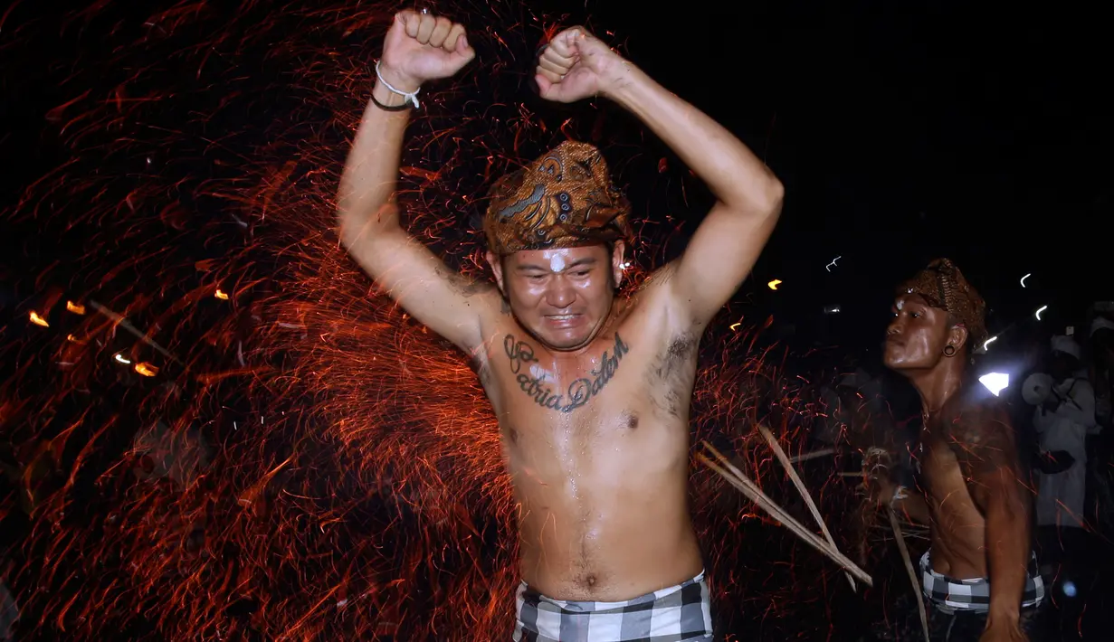 Seorang pria Bali dipukul dengan daun kelapa yang menyala saat ritual Lukat Gni di Klungkung, Bali (16/3). Lukat gni dapat diartikan sebagai tradisi pembersihan atau penyucian bhuana alit dan bhuana agung. (AP Photo / Firdia Lisnawati)